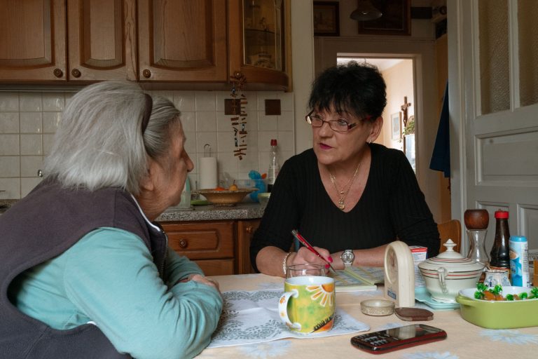 Zwei Frauen sitzen im vertrauten Gespräch am Küchentisch
